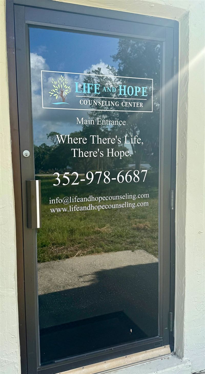 The main entrance to Life and Hope Counseling Center, with the logo, the words Where There's Life, There's Hope, and the phone number 352-978-6687 on the glass door